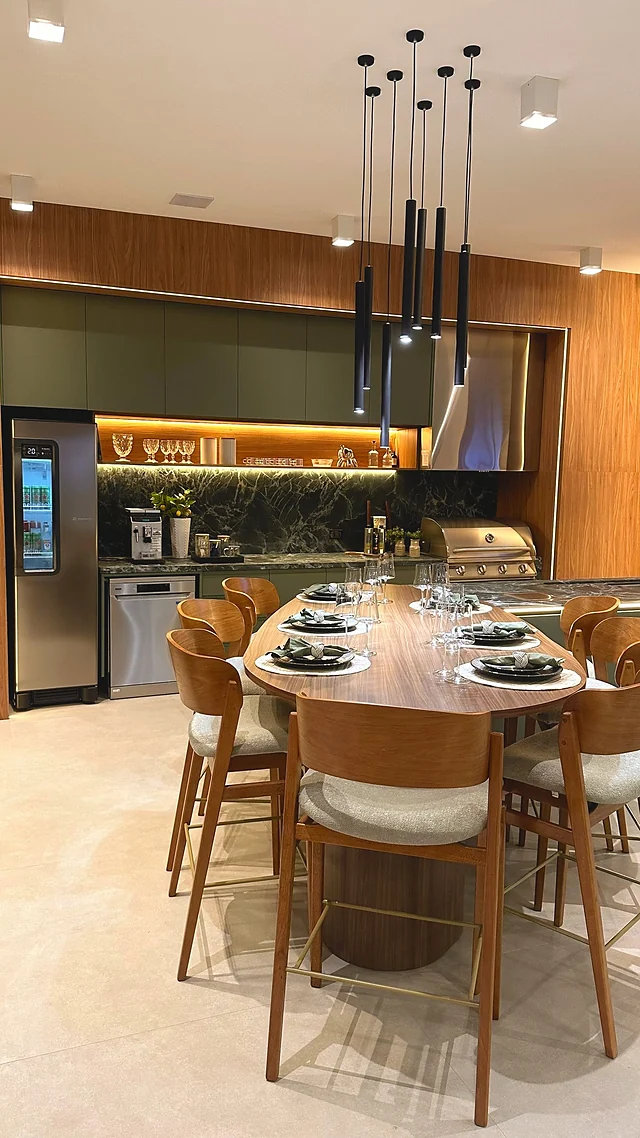 Cozinha gourmet com mesa posta para oito lugares, ilha com banquetas e pendentes, iluminação embutida