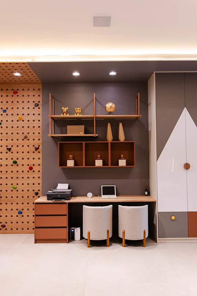 Quarto infantil com parede de escalada em painel perfurado, bancada de estudos para dois, nichos e armário
