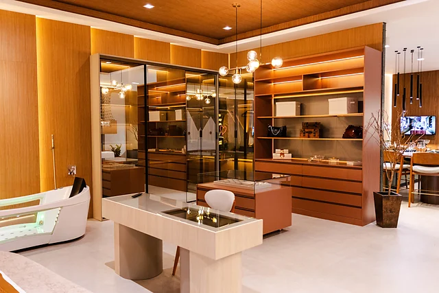 Closet de casal com portas de vidro, prateleiras iluminadas e penteadeira com tampo de vidro